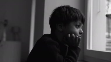 Depresyondaki çocuk pencerenin kenarında dikilip hüzünlü, iç karartıcı, tek renkli, dramatik siyah-beyaz ifadeyle bakıyor. çocuk yalnızlık hissediyor.