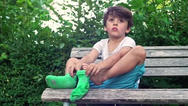 Ребенок Чистит Ноги Перед Применением Носков Отвлекается Пейзажи Парка — стоковое видео