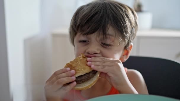 Μικρό Αγόρι Απολαμβάνει Στην Κατανάλωση Σπιτικά Burger Στο Σπίτι — Αρχείο Βίντεο