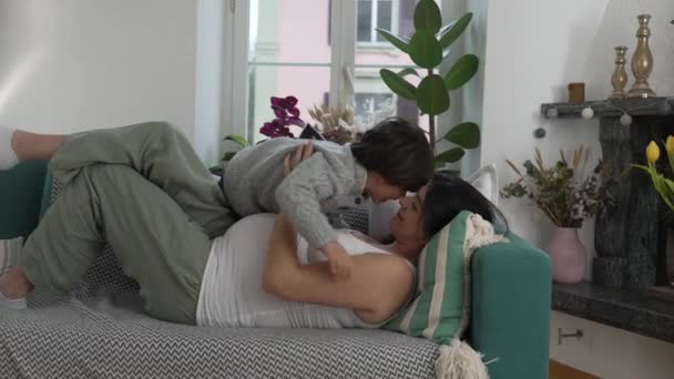 怀孕的母亲和孩子躺在沙发上休息时拥抱在一起 这是父母和5岁儿子之间真正的幸福关系 — 图库视频影像