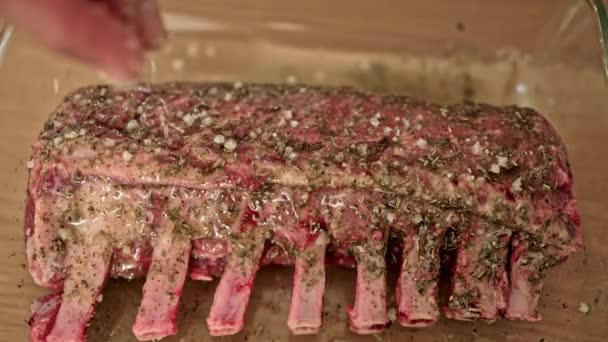 Χέρια Sprinkle Χοντρό Αλάτι Και Πρόστιμο Βότανα Πάνω Rack Lamb — Αρχείο Βίντεο