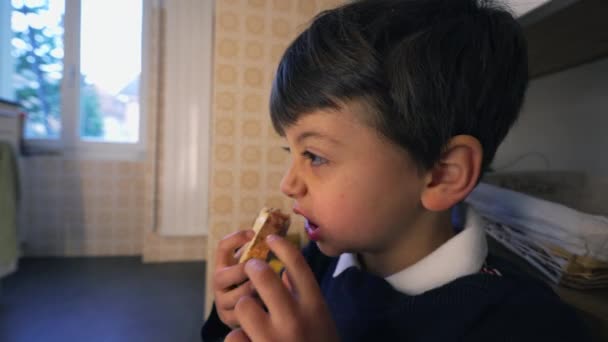 孩子们吃着奶酪面包 下午吃着零食 妈妈在后面打扫厨房 小男孩吃了一小口 — 图库视频影像