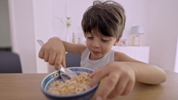 おいしい朝食 小さな男の子は牛乳で穀物を食べることに興奮しました — ストック動画
