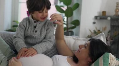 Hamile bir annenin annelik sevinci kanepeye uzanırken 5 yaşındaki oğlu karnını ovaladı, şefkatli bir ilişki yaşadı, özgün bir sahneydi.