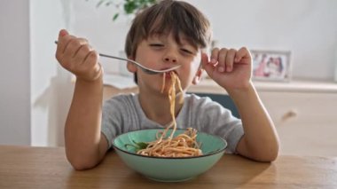 Küçük çocuk çizgi filmlerdeki gibi makarnayı yudumluyor.