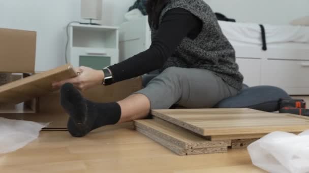 Женщина Сидящая Полу Распаковывает Куски Дерева Коробки Подготовка Сборке Мебели — стоковое видео