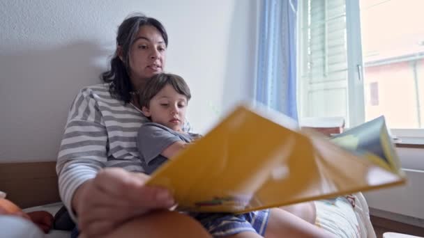 魅了された子供 ママが物語を読むようにイラストを観察する — ストック動画