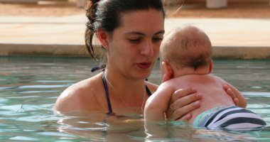 Mother and newborn baby at swimming pool water interaction