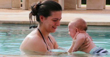 Mother holding baby at the swimming pool