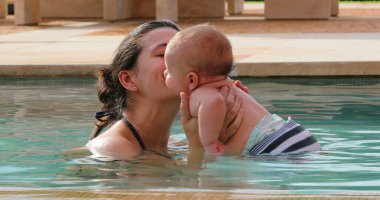 Happy mother with newborn baby in swimming pool water