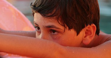 Yüzme havuzunda düşünceli bir genç çocuk.