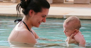 Mother holding baby at the swimming pool