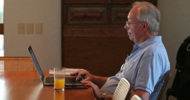 Dizüstü bilgisayarın önünde çalışan dürüst yaşlı bir adam.