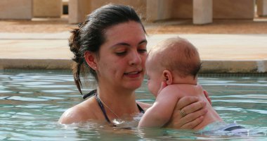 Mother holding baby at the pool water