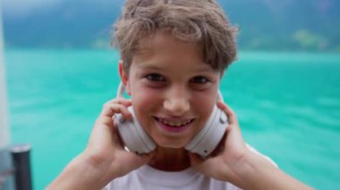 Mutlu ergen çocuk kulaklıkları kulaklıktan çıkartıyor, genç çocuğun yakın plan portresi müzik dinlemeyi ve ses dinlemeyi bırakıyor.