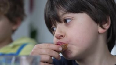 Kahvaltıda jöleli ekmek yiyen, karbonhidrat yiyen küçük çocuğun yakın plan yüzü.