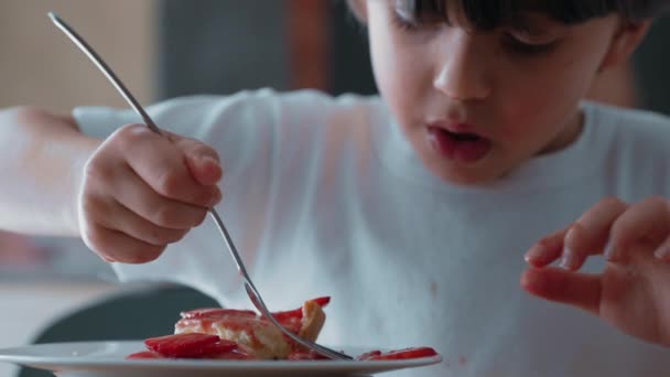 Молодий Хлопчик Делікатно Вибирає Полуничні Скибочки Чізкейку Насолоджуючись Солодким Десертом — стокове відео