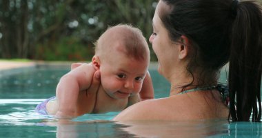 Mother and baby at the swimming pool holding toddler son