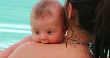 Mom holding baby boy at the pool