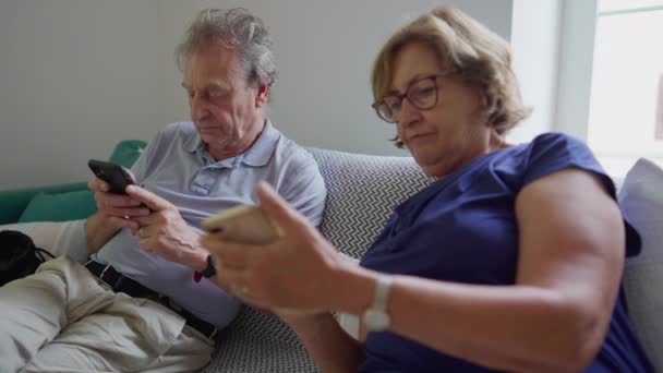 老两口坐在沙发上凝视着屏幕 年长的已婚男女使用现代技术 手持智能手机 — 图库视频影像