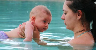 Mother holding baby at the swimming pool