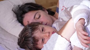 Uyku Saati, anne öğle uykusunu rahatlatmak için çocuğunu yatakta kucaklıyor.