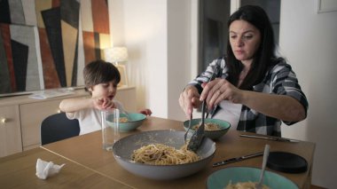 Akşam yemeği - Anne tabakta spagetti servis ederken, oğul yemek yerken, evde bono beslerken