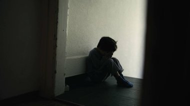 Hüzünlü ve Yalnız Genç Çocuk Karanlık Koridorda Oturuyor, Yüzü Ellerde Saklanıyor, Duygusal Sıkıntıyı ve Aile Kargaşasını Sembolize Ediyor