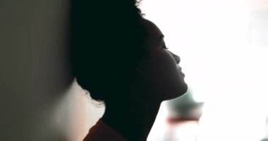 Üzgün, düşünceli, genç Afrikalı Afrikalı Amerikalı kadın duvara yaslanıyor ve zor zamanlarda depresyonla boğuşan melankolik düşünceli bir ifadeyle pencereye bakıyor.