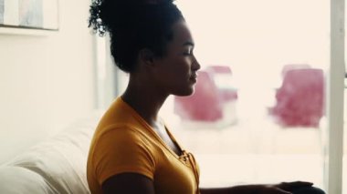 Evde tek başına oturan genç siyahi bir kadının profili. 20 'li yaşlarda Afro-Amerikan bir kadının derin derin bakışları.