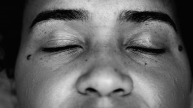 Sessiz meditasyonda gözlerini kapayan genç bir siyahi kadının makro yakın çekimi. Afrika kökenli 20 'li yaşlarda dinleniyor.