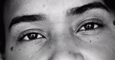 Tek renkli, siyah beyaz kameraya bakan genç bir siyahi kadının yoğun makro-yakın çekim yüzü.