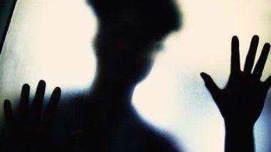 Bulanık camların arkasındaki gölgeli figür, Zihinsel Mücadele, Depresyon Teması. Tuzaktan kaçmak isteyen bir kadın.