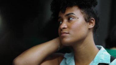 Düşünceli genç Afrikalı Amerikalı metro trenine biniyor. Pencere kenarına oturmuş, manzaraya bakıyor. Yeraltı ulaşımıyla geçip gidiyor.