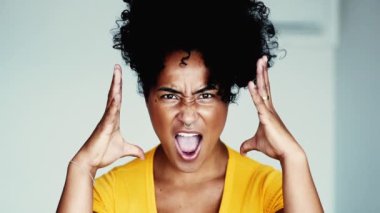 Üzgün genç bir siyah kadın kameraya bağırıyor, elleriyle el kol hareketi yapıyor ve suratını buruşturuyor aşırı öfke ve hüsran hissediyor. 20 'li yaşlardaki birinin öfkeli duyguları.