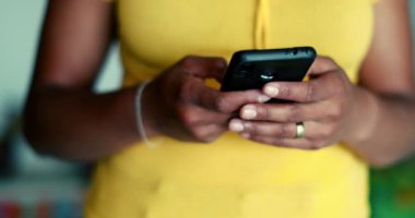 Genç siyahi bir kadın ayakta cep telefonu kullanıyor. Afrikalı Amerikalı 20 'li yaşlarda elinde modern teknolojiyle telefon tutan biri.