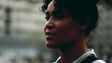 Meditasyon yapan genç siyahi bir kadın gün batımında dışarıda durup derin bir nefes alıyor. Rahatlamaya çalışan düşünceli bir insan.