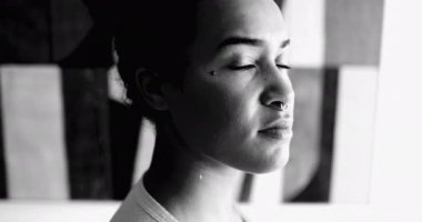 Afro-Amerikan genç kadın dramatik siyah-beyaz portre ciddi bir ifadeyle kameraya bakıyor. 20 'li yaşlardaki yetişkin bir kız tek renk konusunda kendini güçlü hissediyor.