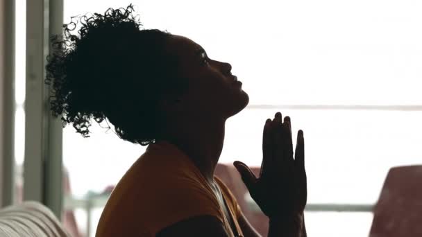 自宅で神に祈る若い黒人女性のシルエットプロフィール 困難な時期にヘルプとサポートを求める20代の人 HopeとFaithを持つ — ストック動画