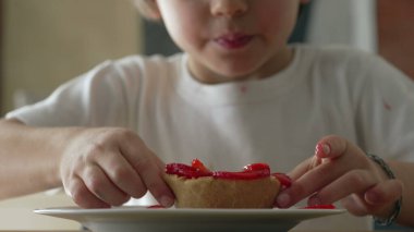 Cheesecake tatlısının tadını çıkaran küçük bir çocuk. 5 yaşındaki çocuk tabaktan şekerli yiyecek alıyor.