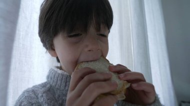 Çocuk sandviçi, yakın çekim eli ve yüzü öğleden sonra zengin karbonhidrat yiyen küçük bir çocuğun.