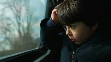 Trenin camına oturmuş manzarayı seyreden küçük bir çocuk gözlerini kısarak güneş ışınlarına karşı koruyor. 5 yaşında, Kafkas çocuk gezgin.