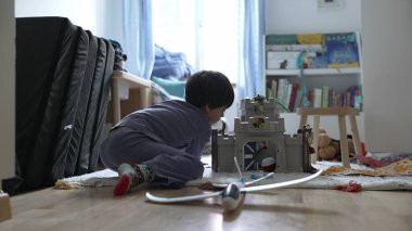 Yaratıcı çocuk sabahları pijama giyerek evdeki yatak odasında oynuyor. Küçük çocuk oyuncak uçağını aldı ve oyuna daldı. 5 yaşında beyaz bir çocuk.