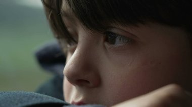 Düşünceli çocuk, derin derin bakışlarla trenle seyahat ederken gözlerini ve yüzünü kapat. Düşüncelere dalmış küçük bir çocuğun düşünceli ifadesi.