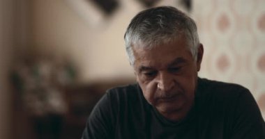 Bunalımlı son sınıf öğrencisi evde yalnız ve umutsuzluk içinde, yaşlı beyaz bir adamın yakın çekimi hüzünlü bakışlar, buruşuk buruşuk saçlar ve portreler içinde kaybolmuş.