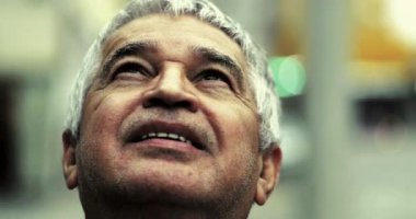 Derin düşüncelere dalmış yaşlı bir adam yakın plan çekimlerinde yukarı bakıyor umutla ve inançla gülümsüyor ve ruhsal olarak tatmin olduğunu hissediyor.