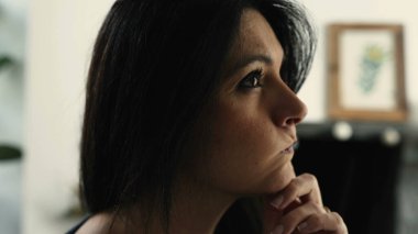 Düşünceli 30 'lu yaşlardaki kadın sorunlara derin düşünceli bir ifadeyle çözüm arıyor, kapalı bir evde kapalı bir yüz.