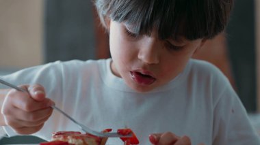 Young Boy Delicately Selecting Strawberry Slices from Cheesecake/ Enjoying Sweet Dessert with Fork after Dinner clipart