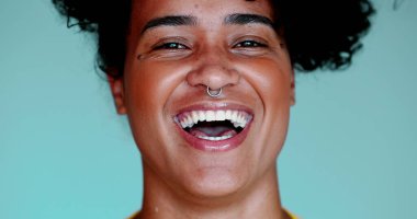 Genç siyahi bir kadın gülümsüyor ve gülüyor. Gerçek otantik yüz ifadesi. 20 'li yaşlarda Afrika kökenli biri kameraya bakıyor.