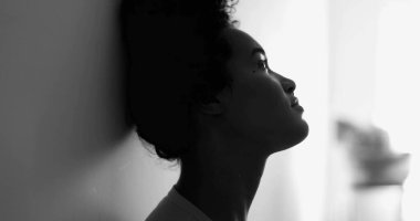 Düşünceli Afro-Amerikan Kadın Duvara yaslanıyor, Melankolik İfadeyle Pencereden dışarı bakıyor, Zor Zamanlar 'da Depresyonla yüzleşiyor siyah-beyaz